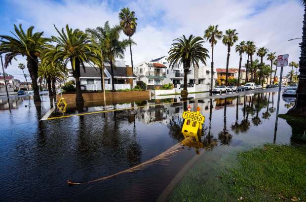 The sun begins to come out over a flooded 18th Street at Olive Avenue in Huntington Beach as a winter storm brought wind, rain and flooding to Orange County on Thursday morning, January 5, 2023.(Photo by Mark Rightmire, Orange County Register/SCNG)