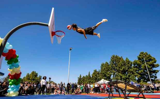 A member of the TNT Dunk Squad flies through the air as children and members of the community joined officials with the city of Santa Ana to celebrate a refurbished basketball court at Portola Park in Santa Ana on Tuesday afternoon, April 4, 2023. The city teamed up with a non-profit, Project Blackboard, and BJ's Restaurant & Brewhouse, which funded the $75,000 basketball court project. (Photo by Mark Rightmire, Orange County Register/SCNG)
