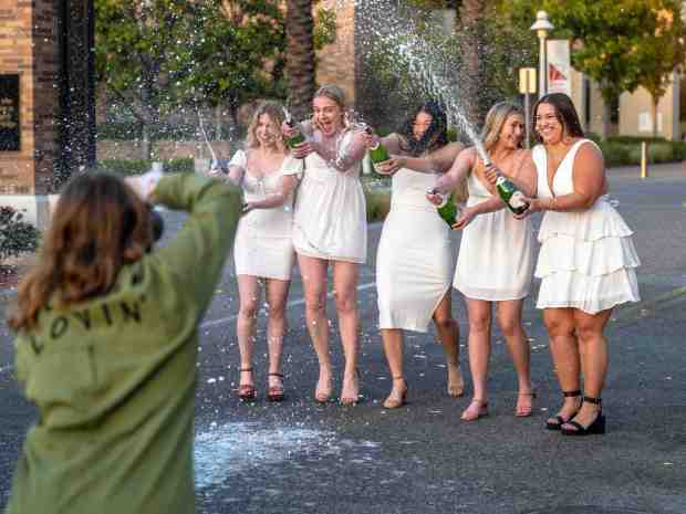 Students from Kappa Alpha Theta sororiety at Chapman University in Orange have their graduation photos taken as they uncork bottles of champagne on Sunday, April 16, 2023. (Photo by Mark Rightmire, Orange County Register/SCNG)