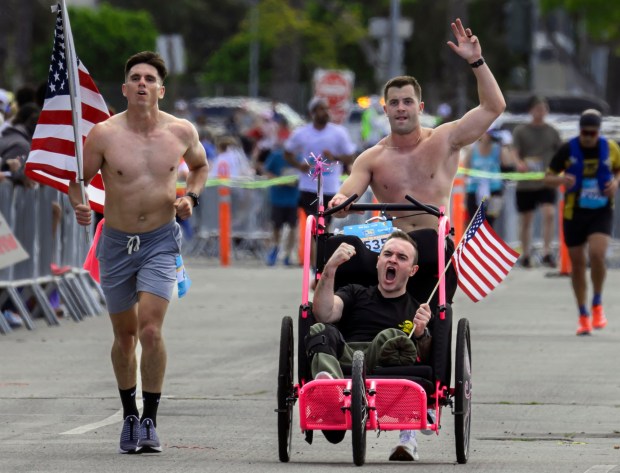 Marine veteran Collin McSpirit with his brother Sean McSpirit, behind, and Mats Bjurman, left, both 1st Lts. in the Marine Corps, approach the OC Marathon finish in Costa Mesa on Sunday, May 7, 2023. McSpirit, who lost his leg in a motorcycle accident, walked the last few feet of the run. (Photo by Mindy Schauer, Orange County Register/SCNG)