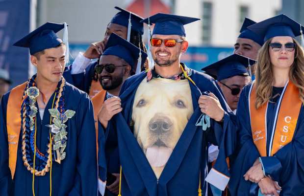 Joseph Borgese, center, pulls back his gown to reveal a photo of his dog Siegfried during the commencement ceremonies for the College of Education at Cal State Fullerton in Fullerton on Monday, May 22, 2023. Over 13,000 CSFU graduates will participate commencement ceremonies May 22-25. (Photo by Leonard Ortiz, Orange County Register/SCNG)