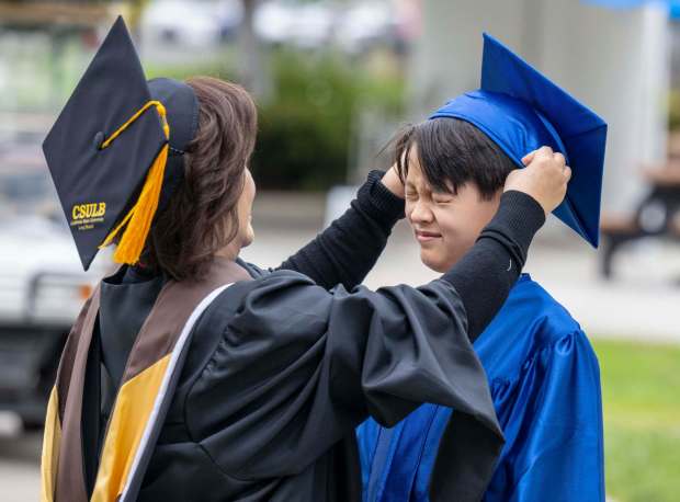 Tiffany Tran, left, a counselor at Irvine Valley College, places the cap on Tycho Elling, 11, of San Juan Capistrano, just prior to commencement at Irvine Valley College in Irvine on Thursday, May 25, 2023. Elling is the youngest 2023 graduate and the youngest student to graduate in IVC's 38 years. (Photo by Mark Rightmire, Orange County Register/SCNG)
