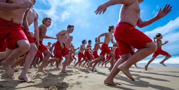 Hundreds of participants in the Newport Beach Junior Lifeguard program run down the beach and into the water at the start of a buoy swim near the Balboa Pier on Ben Carlson Day in Newport Beach on Thursday, July 6, 2023. Carlson, a Newport Beach lifeguard, died saving a swimmer during a big swell in 2014. (Photo by Mark Rightmire, Orange County Register/SCNG)