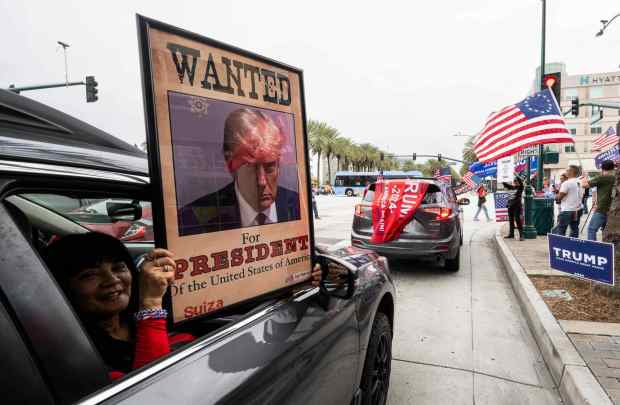 A woman holds a pro-Trump poster as she passes a rally at Harbor Blvd. and Katella Ave. in Anaheim, CA on Friday, September 29,2023. Trump, along with other Republican candidates, were speaking at the California GOP convention at the Anaheim Marriott. (Photo by Paul Bersebach, Orange County Register/SCNG)
