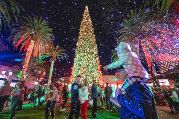 Families visiting Fashion Island in Newport Beach enjoy the 50 Nights of Coastal Lights which includes snowfall, music and a choreographed light display and take photos by the 90-foot Christmas tree on Friday, December 8, 2023. (Photo by Mark Rightmire, Orange County Register/SCNG)