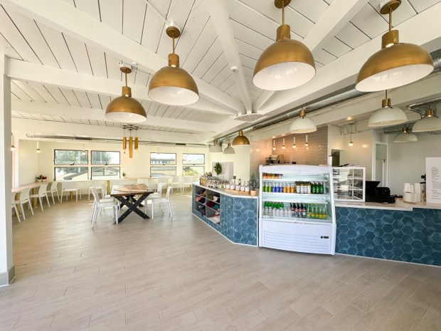 White interiors with exposed beams, vaulted ceilings, yellow dangling lamps and a coffee counter in navy blue.