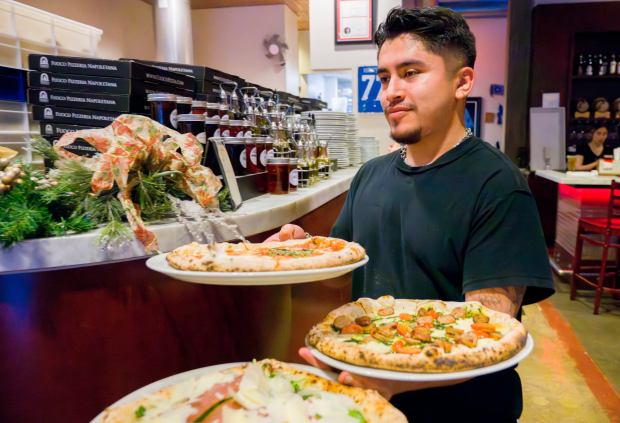 Server Christian Rico delivers pizzas to diners at Fuoco Pizzeria Napoletana in Fullerton on Wednesday, Jan. 3, 2024. Fuoco Pizzeria Napoletana is located two blocks from the Fullerton Train Station. (Photo by Leonard Ortiz, Orange County Register/SCNG)