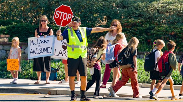 Larry Lanterman, a recently widowed 87-year old crossing guard at Oso Grande Elementary School helps children cross the street in Ladera Ranch on Tuesday, October 17, 2023. On his last day of work a group of parents and students surprised Lanterman at the cross walk with signs of support and a fund raising page for him to help him to raise money as his only means of income currently is delivering for UberEats. Lanterman announced that he might be at the crosswalk for another 3-weeks since his planned move to Palm Springs was delayed. (Photo by Leonard Ortiz, Orange County Register/SCNG)
