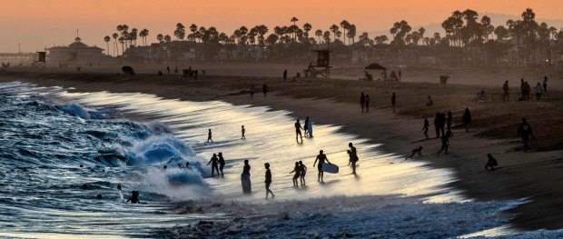 The golden glow of the sunset fills the air as beach goers play in the waves while the high tide pushes onshore just north of the Balboa Pier in Newport Beach on Wednesday, Aug. 2, 2023. (Photo by Mark Rightmire, Orange County Register/SCNG)