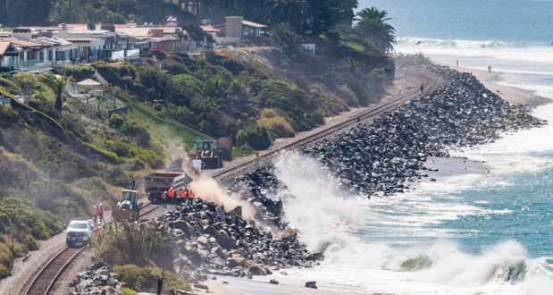 Workers dump rocks along the railroad tracks as waves crash on the rip rap in south San Clemente in September 2021. Train service was again halted through the area since September 2022. (Photo by Paul Bersebach, Orange County Register/SCNG)