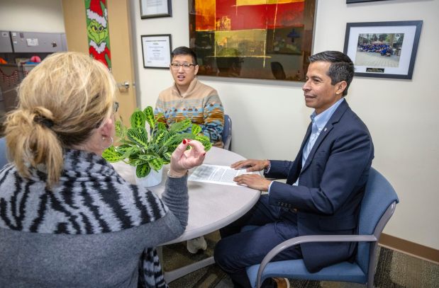 Sergio Contreras, right, executive director of United for Student Success at the OC United Way in Irvine, speaks with staffers, Michelle Murphy, left, senior director, public affairs, and Timothy Pyon, center, systems administrator, in his office on Friday, Dec. 22, 2023. (Photo by Mark Rightmire, Orange County Register/SCNG)