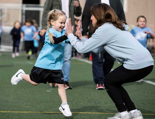 Four-year-old Elle Page gets high fives from her teacher Lisa Garceau during a jog-a-thon at St. Mary's School in Aliso Viejo, CA on Friday, February 17, 2023. The event was a fundraiser for the school's athletic department. (Photo by Paul Bersebach, Orange County Register/SCNG)