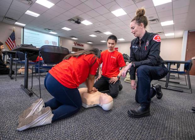 As Amanda Brady, right, an EMT and community educator for Falck Mobile Health, looks on, Gabrielle Agor, left, of Anaheim, and Kenny Nguyen, center, of Westminster, practice learning CPR during a class at Falck's office in Orange on Wednesday, June 21, 2023. Orange County United Way's United for Student Success initiative has partnered with Falck to provide EMT training to 20-30 Orange County students and introduce them to a career as an EMT. (Photo by Mark Rightmire, Orange County Register/SCNG)