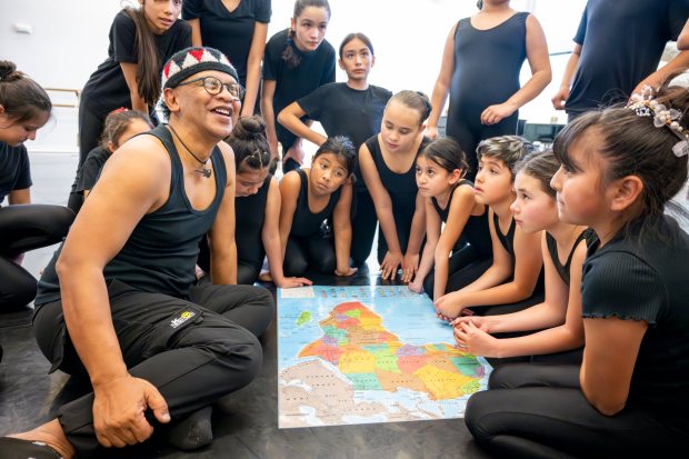 Students from The Wooden Floor join performer Sameola xe2x80x9cSammy Andriamalalaharijaona, left, of Madagascar as he points out his home country on a map in Santa Ana on Friday, Feb. 2, 2024. The Wooden Floor partnered with Chapman Universityxe2x80x99s Musco Center for the Arts to provide six master classes to all The Wooden Floor student, free of charge. ..Small Island Big Song is an artistic collective of singers, musicians, and dancers from island nations in the Indian and Pacific Oceans that perform their traditional dances and songs. Small Island Big Song will be performing at the Musco Center for the Arts on Feb. 3. (Photo by Leonard Ortiz, Orange County Register/SCNG)